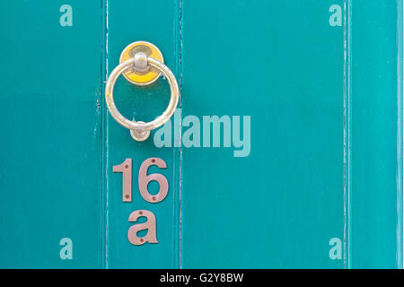 Light blue English period wooden front door with ornate iron door knocker. House number position under door knocker. Soft natura Stock Photo