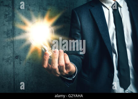 Business creativity and vision concept with elegant adult businessman holding bright light bulb as metaphor of new ideas in hand Stock Photo
