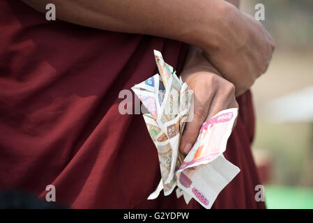 A Buddhist monk with a handful of banknotes, Demoso, Kayah State, Myanmar Stock Photo