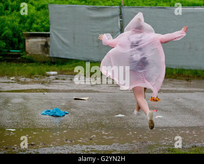 Nuremberg, Germany. 04th June, 2016. A woman jumps across a puddle during a rain shower at the 'Rock im Park' (Rock in the Park) music festival in Nuremberg, Germany, 04 June 2016. More than 80 bands are set to perform at the festival until 05 June. Photo: DANIEL KARMANN/dpa/Alamy Live News Stock Photo
