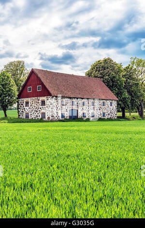 An old stone barn with wooden roof set in the rural countryside of Swedens Skane region. Stock Photo