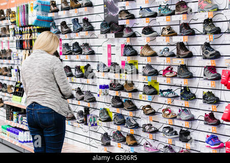 A customer looks at walking shoes, boots and sandals on sale in Go Outdoors sports shop. Stock Photo