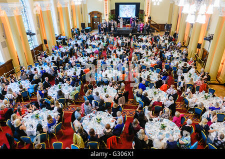 Around 200 people, mainly women,  attending a formal dinner in a large hall. Stock Photo