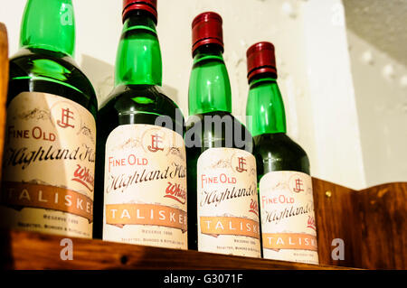 Four bottles of Talisker Highland Malt Whiskey on a wooden shelf.
