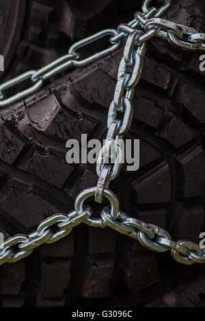 Close up shot of some chains wrapped around a car's tire. Stock Photo