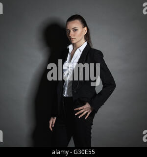 Portrait of young businesswoman in black suit on dark background Stock Photo