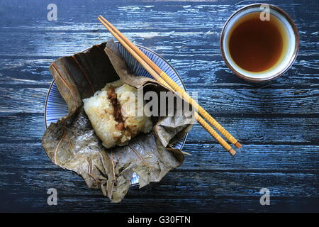 Lo Mai Gai. Steamed parcel of sticky rice with pork, shrimp, and egg in lotus leaf. Flat-lay view. Stock Photo