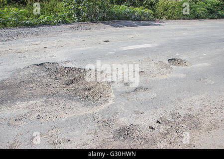 Damaged road in the countryside, damaged asphalt road with potholes caused, Poor road. Stock Photo