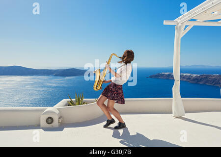 Young woman playing on saxophone against the background of the sea Stock Photo
