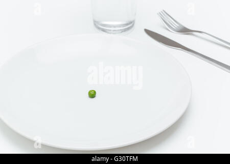 Plate with one small green pea on served table over white background Stock Photo