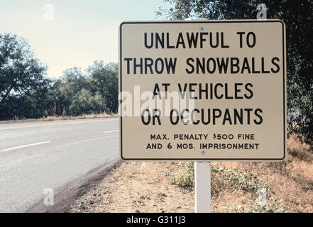 In midsummer, motorists often laugh at a roadside sign that warns against throwing snowballs at vehicles or occupants on a mountain highway in San Diego County, California, USA. Come winter, this same scene is often covered with snow and attracts families and visitors from nearby seaside communities to play in the white stuff. Stock Photo