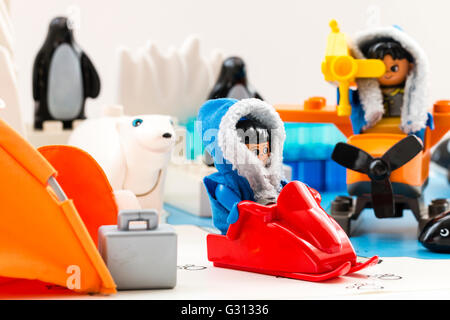 Lego duplo explore Arctic playset. Woman lego figure with jet ski at base camp with man figure filming. Icebergs, whale and penguins in background. Stock Photo