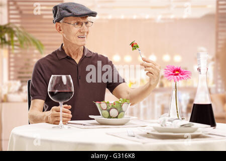 Discontent mature man sitting in a restaurant and looking at their food in disgust Stock Photo