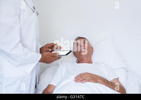 Male doctor standing next to the patient and holding a digital tablet Stock Photo