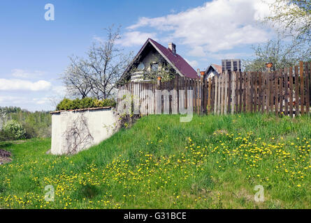 The village is located on the hills which have grown with dandelions. Sunny spring landscape Stock Photo