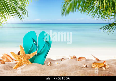Summer flipflop on sandy beach, blur sea on background. Summer exotic relaxation concept Stock Photo