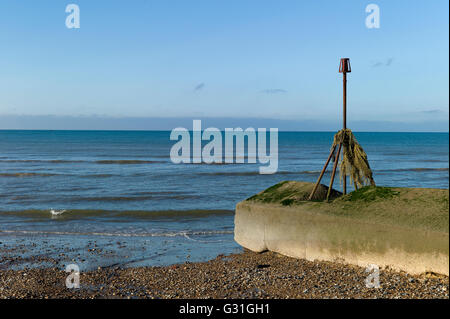 Warning marker draped in old fisherman's net on concrete groyne, Brighton, Sussex Stock Photo