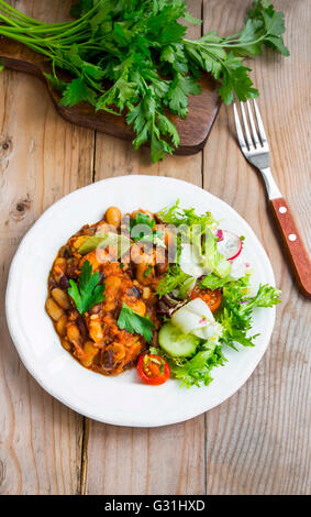 Bean stew with fresh parsley and vegetables salad Stock Photo