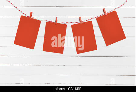 Blank paper or photo frames hanging on the red striped clothesline . Wooden background. Template for your text. Stock Photo