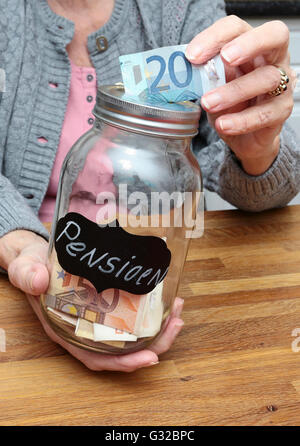 An elderly woman with a money filled jar labelled with the dutch word for pension Stock Photo