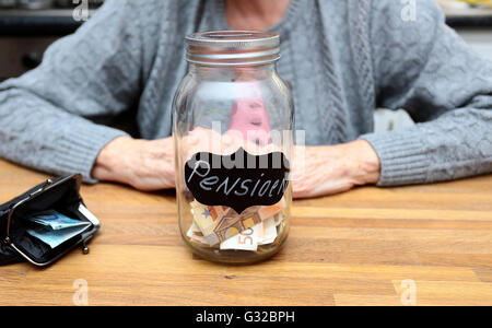 An elderly woman with a money filled jar labelled with the dutch word for pension Stock Photo