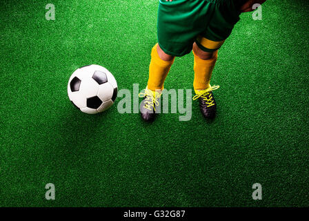 Unrecognizable little football player against green grass, studi Stock Photo