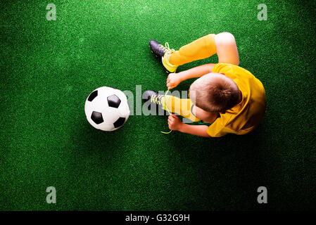 Unrecognizable little football player against green grass, studi Stock Photo