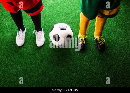 Two unrecognizable little football players against green grass Stock Photo