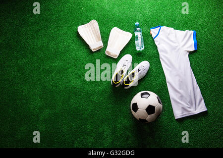 Soccer ball,cleats and various football stuff against artificial Stock Photo