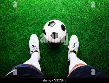 Unrecognizable football player against green grass, studio shot Stock Photo