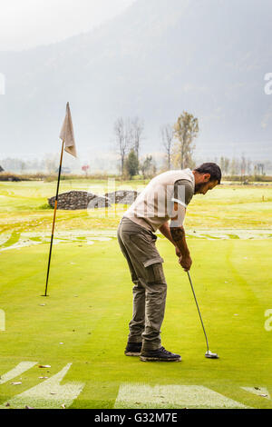 a golf player aiming for the hole on the green with a putter Stock Photo
