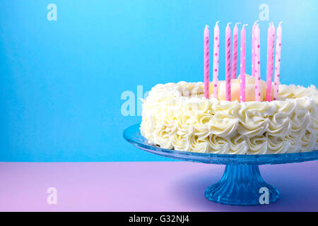 Celebration showstopper white chocolate mudcake with pink candles against a blue and pink background. Stock Photo