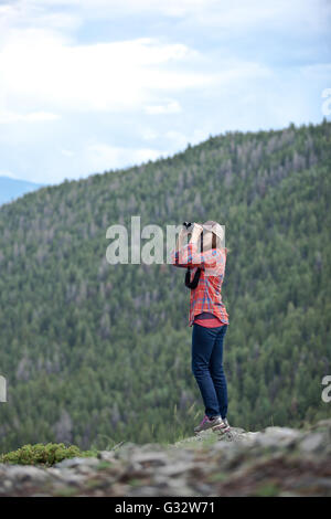 Side view of a woman bird watching, looking through binoculars in a ...
