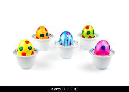 Painted easter chicken eggs standing in porcelain egg cups isolated on white background Stock Photo