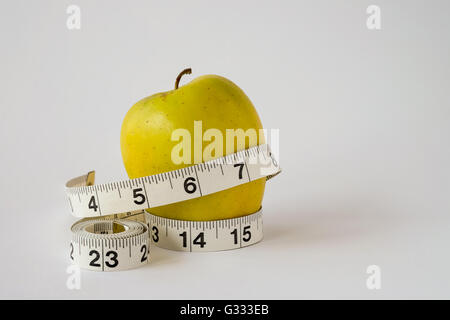 Fresh healthy yellow apple with measuring tape on white background Stock Photo