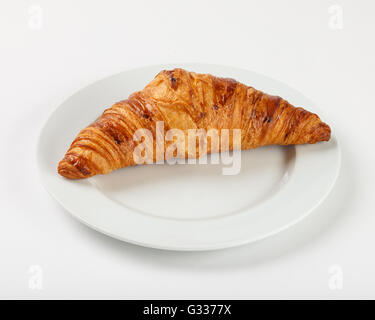 Delicious croissant on the plate on white background. Close up side view. Stock Photo