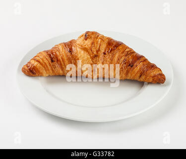 Сroissant on the plate. Close up side view. Stock Photo