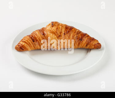 Delicious croissant on the plate on white background. Close up side view. Stock Photo