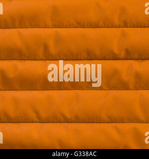 Orange yellow quilted textile with insulation texture. Vertical stripes.  Close up fragment of the top view. Stock Photo
