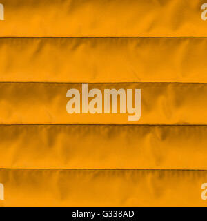 Orange quilted textiles with insulation texture. Vertical stripes.  Close up fragment of the top view. Stock Photo