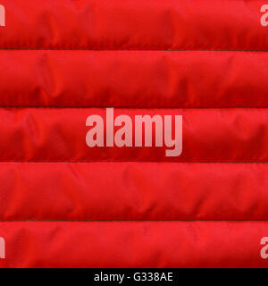 Red quilted textiles with insulation texture. Vertical stripes.  Close up fragment of the top view. Stock Photo