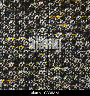 Woven woolen fabric texture. Black, white, orange, yellow complicated melange. Close up fragment of the top view. Stock Photo