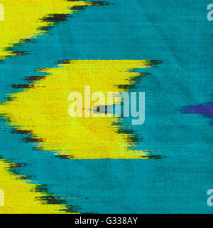 Uzbek silk atlas Ikat texture. Yellow, turquoise and blue ornament. Close up fragment of the top view. Stock Photo