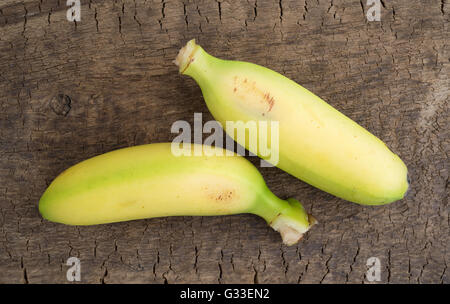Top view of two small bananas on an old worn wood board. Stock Photo