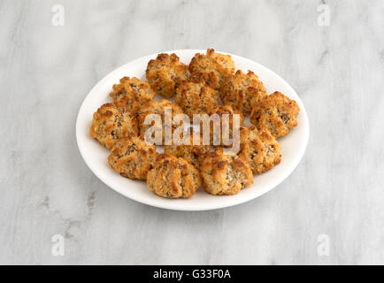 Several chocolate chip macaroons on a white plate atop a marble table top. Stock Photo