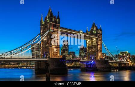 Illuminated Tower Bridge in London after sunset with London’s financial district at the background Stock Photo