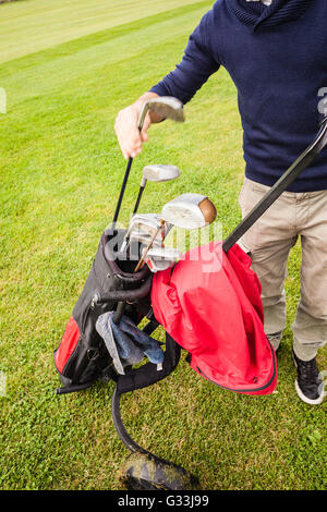 a golf player playing on a beautiful golf course and a golf bag full of golf clubs Stock Photo