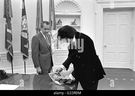 Elvis Presley presents an autographed photograph to U.S President Richard M. Nixon in the Oval Office at the White House December 21, 1970 in Washington, DC. The meeting was initiated by Presley, who wrote Nixon a six-page letter requesting a visit with the President and suggesting that he be made a 'Federal Agent-at-Large' in the Bureau of Narcotics and Dangerous Drugs. Stock Photo