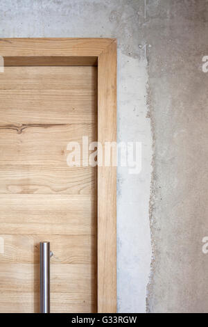 Wooden door casing and concrete wall. Wolfson College Auditorium, Oxford, United Kingdom. Architect: Berman Guedes Stretton, 2013. Stock Photo