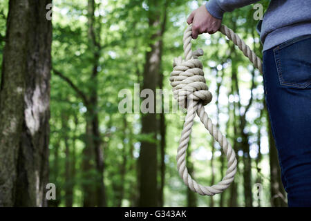 Depressed Man Contemplating Suicide By Hanging In Forest Stock Photo